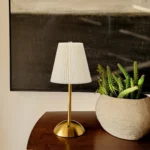 Elixir gold touch sensor lamp with signature pleated fabric shade, emitting a 3000K warm glow for luxury bedside ambiance.